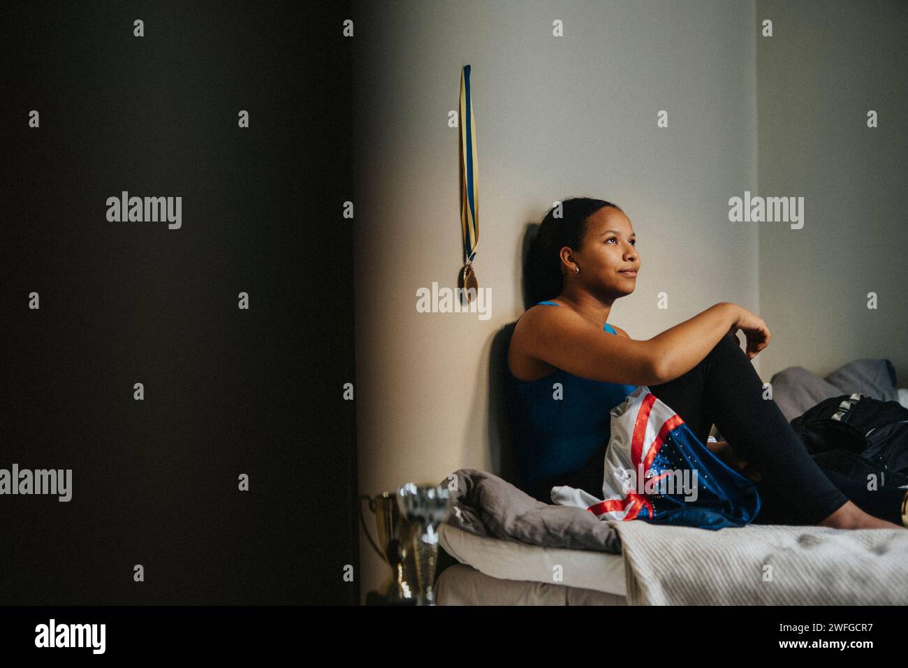 Teenager-Mädchen-Tag träumend auf dem Bett an der Wand im Schlafzimmer zu Hause sitzend Stockfoto