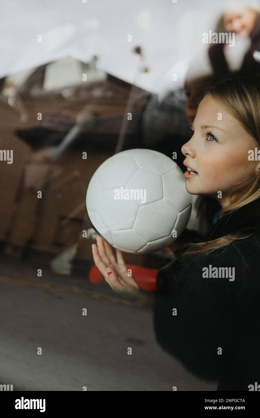 Mädchen mit Fußballtag träumend durch ein Glas Auto gesehen Stockfoto