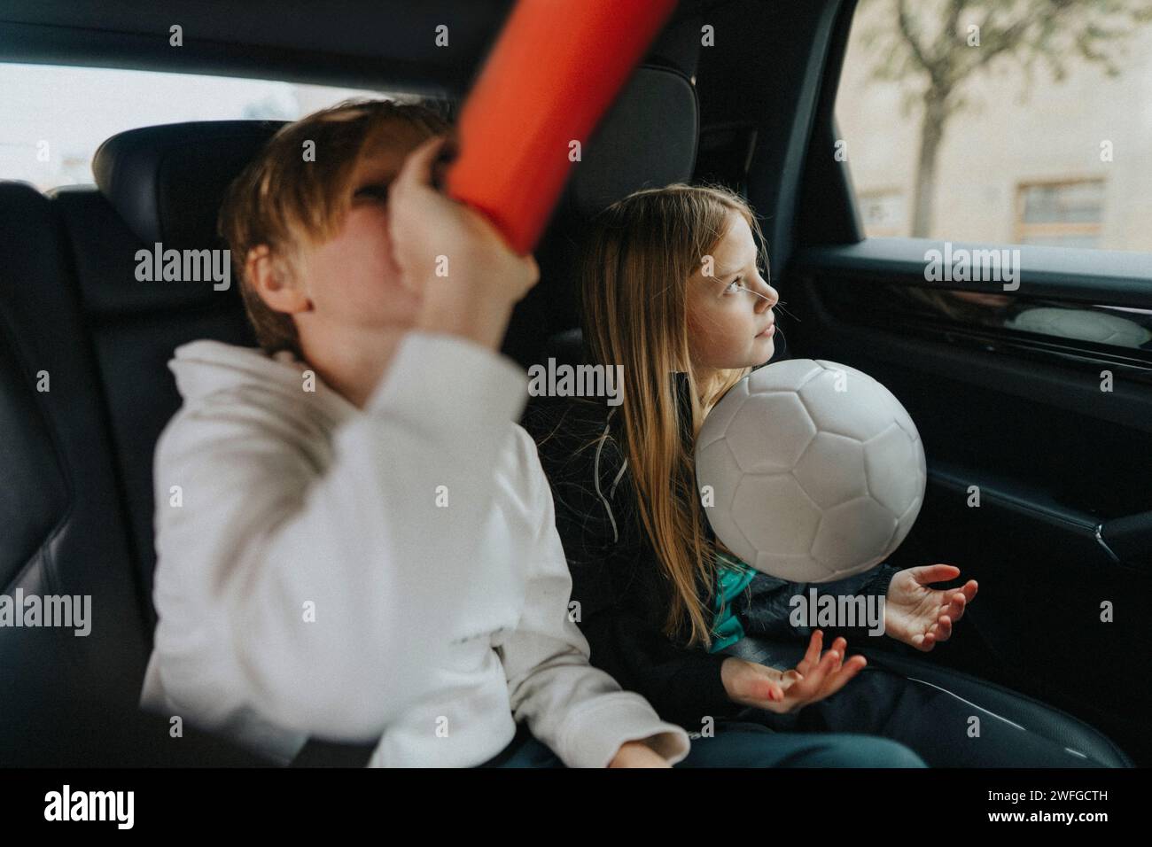 Junge trinkt Wasser während des Wochenendausflugs mit Schwester im Auto Stockfoto