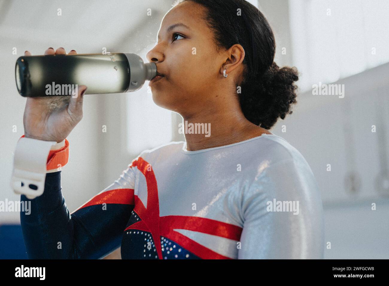 Weibliche Athletin trinkt Wasser aus der Flasche im Fitnessstudio Stockfoto