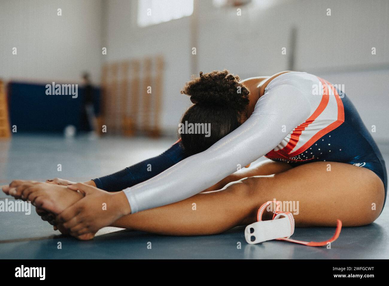 Das Teenager-Mädchen übt Dehnübungen während des Sitzens im Fitnessstudio Stockfoto