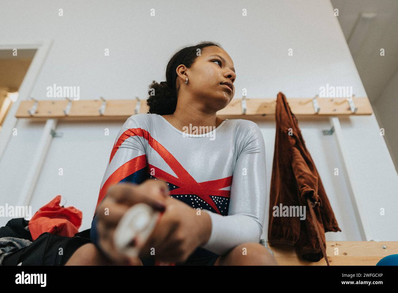 Besinnliches Teenager-Mädchen in Sportkleidung, das in der Umkleidekabine sitzt Stockfoto