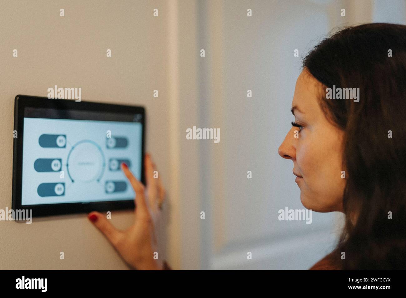 Reife Frau, die ein digitales Tablet für die Temperaturregelung zu Hause verwendet Stockfoto