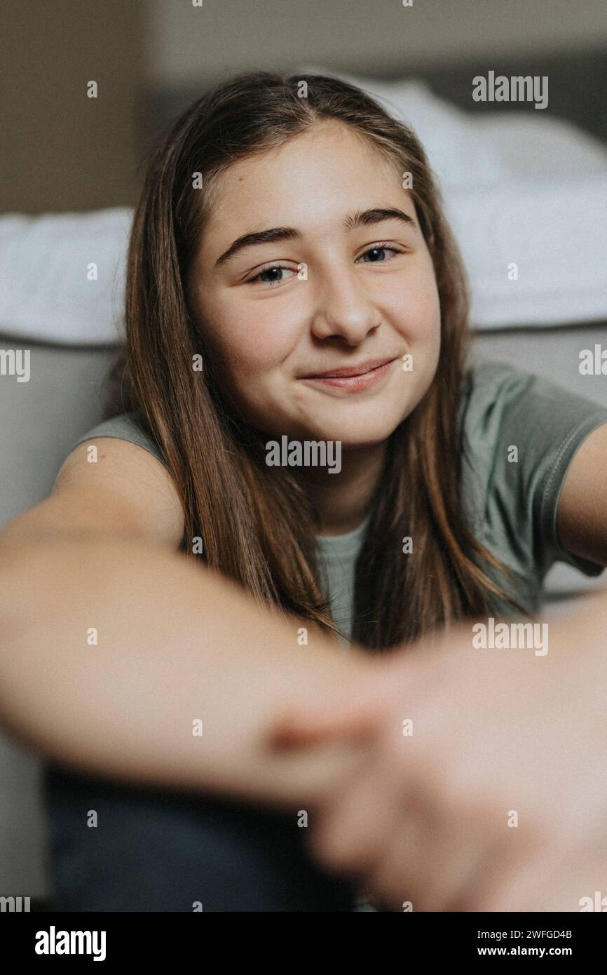 Porträt eines lächelnden vorpubertären Mädchens, das zu Hause sitzt Stockfoto