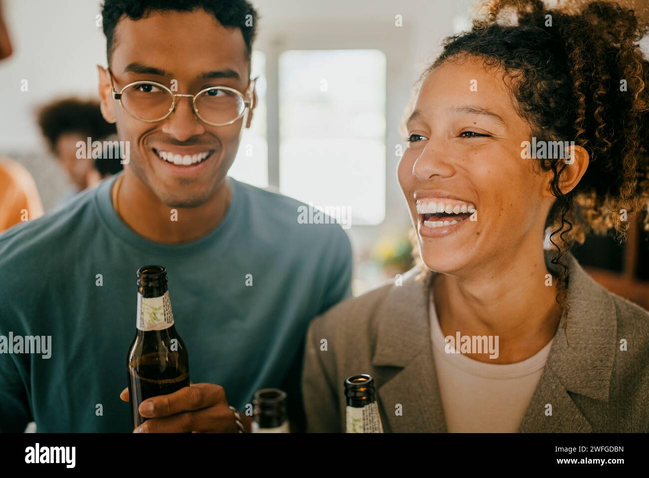 Fröhlicher junger Mann und Frau mit Bierflaschen in der Küche Stockfoto