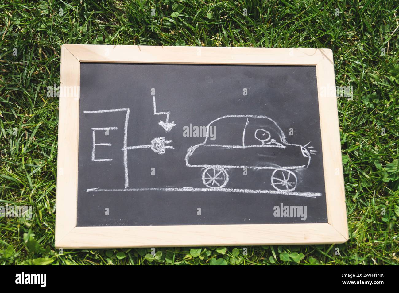 Schwarze Tafel mit einem gezogenen Elektroauto an einer Ladestation, Symbolbild Stockfoto