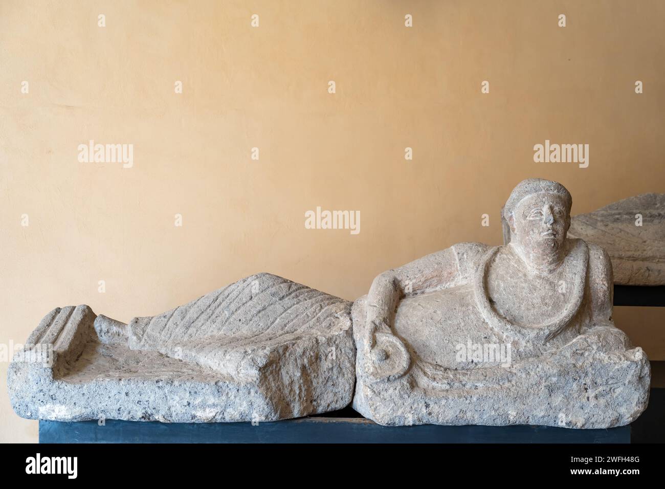 Nahaufnahme einer antiken etruskischen Statue, die in Stein gehauen ist und einen Mann darstellt, der sich niederlegt Stockfoto