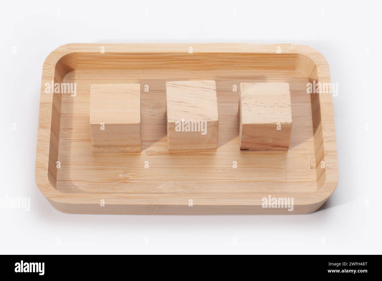 Holztablett mit Würfeln isoliert auf weißer Oberfläche Stockfoto