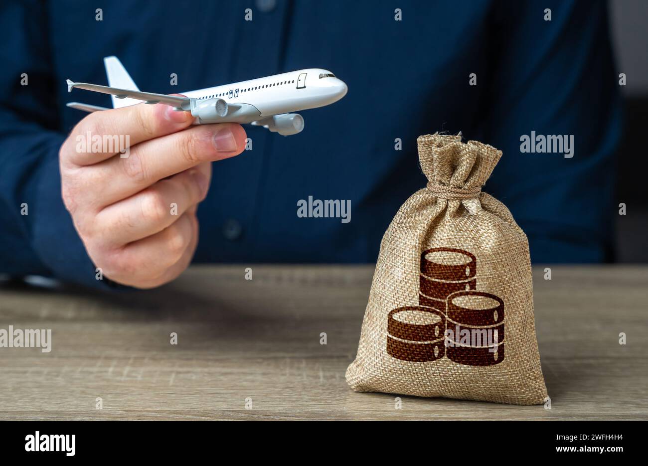 Ein Mann mit einem Flugzeug in der Hand und einem Geldbeutel. Einkommen der Luftfahrtbranche. Budgetzuweisungen. Investitionen in die Entwicklung des Luftverkehrs i Stockfoto