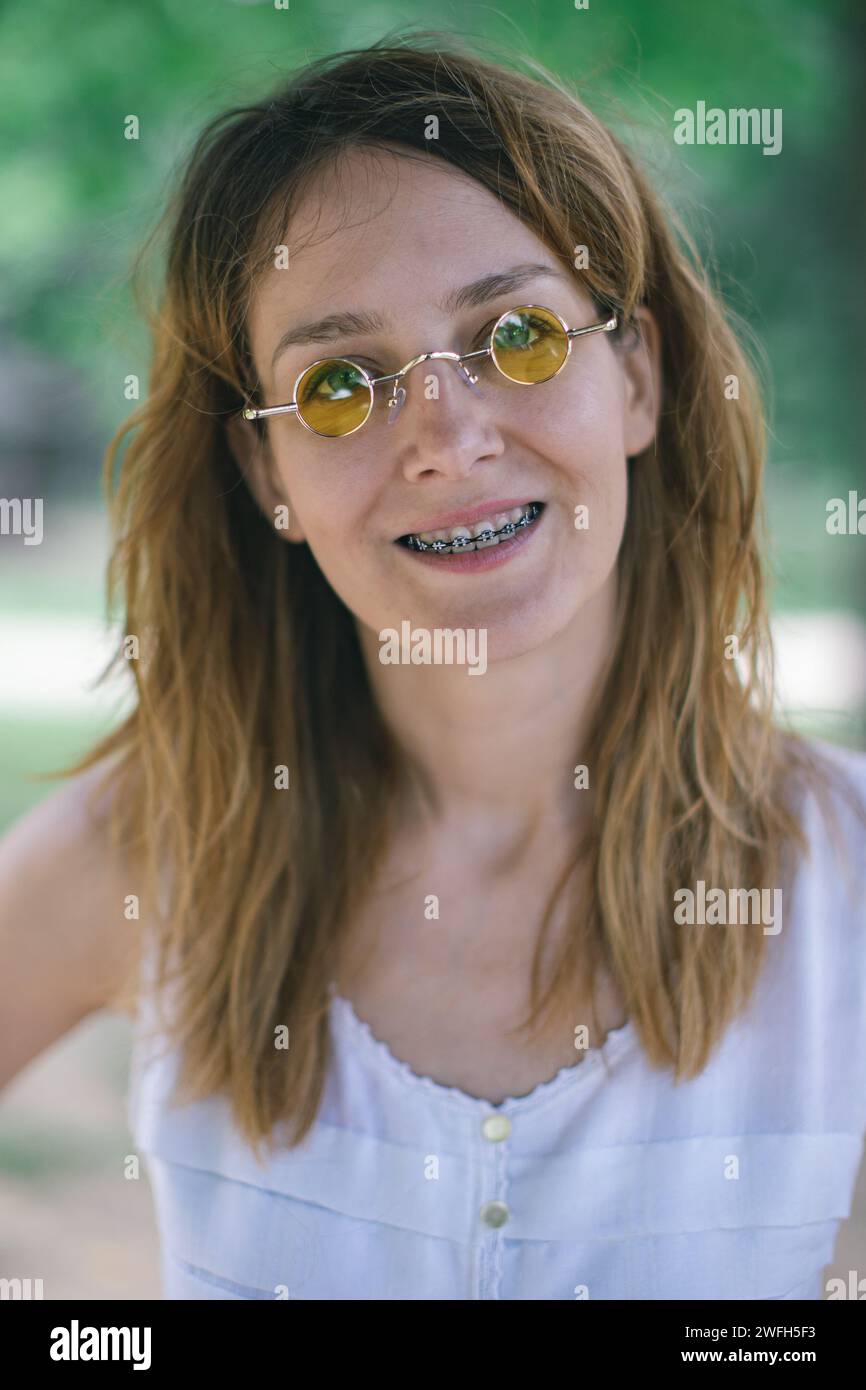 Junge Frau mit gelber Rundbrille und Zahnspange Stockfoto