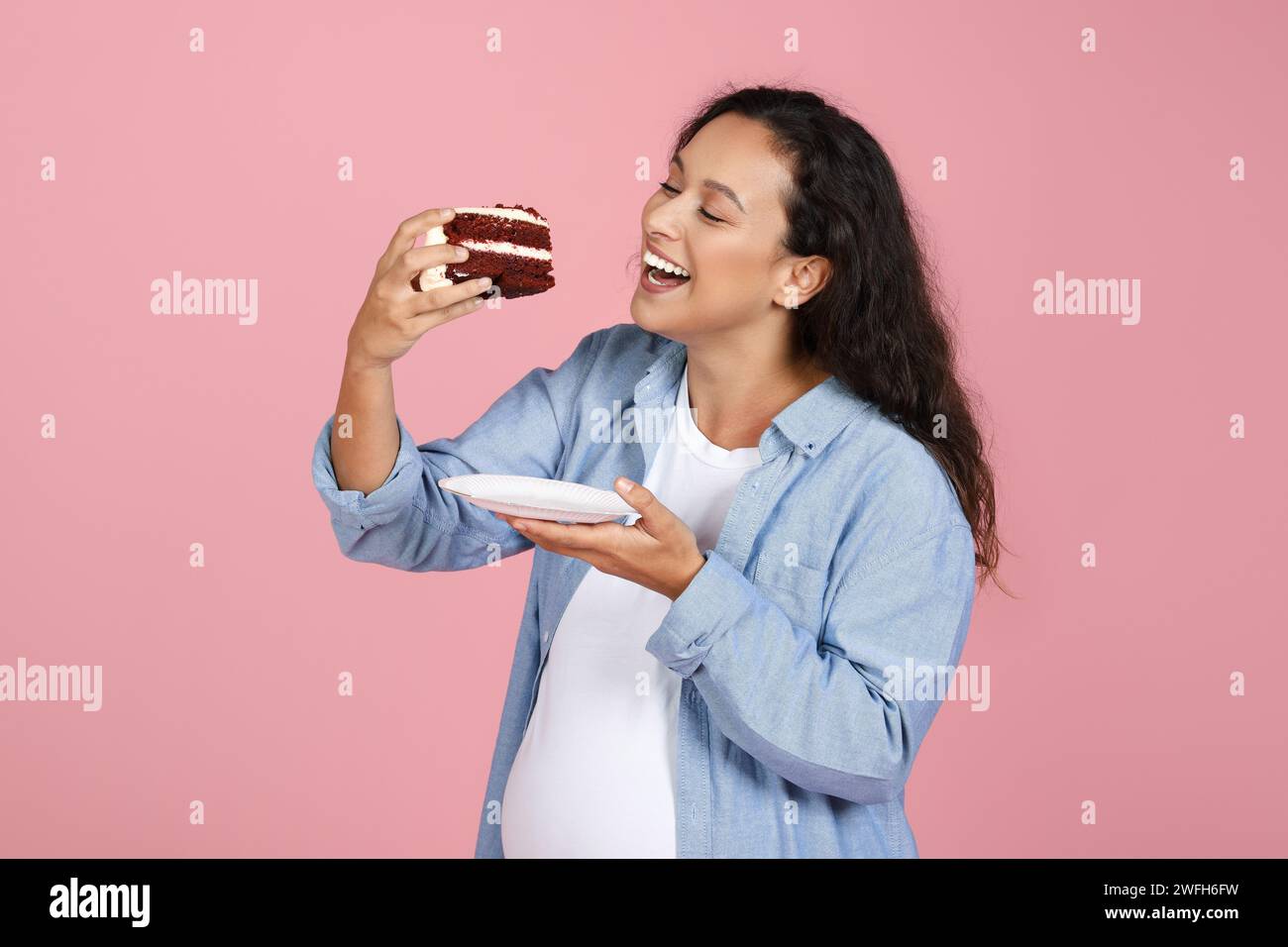 Aufgeregt Schwangere Dame Isst Kuchen, Die Über Rosa Studio Hintergrund Steht Stockfoto
