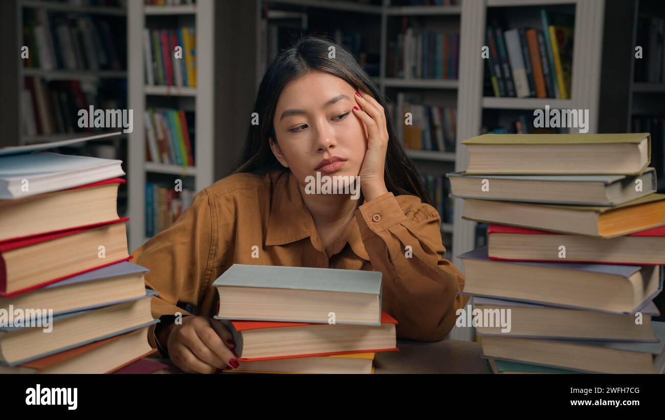 Traurige müde Frau Mädchen Studentin gelangweilt am Schreibtisch mit Büchern in der Universitätsbibliothek faule unmotivierte asiatische Frau, die sich auf schwierige College-Prüfung vorbereitet Stockfoto