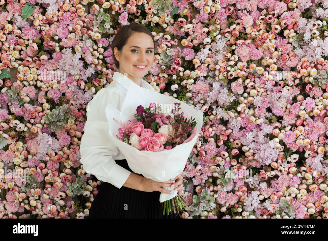 Glückliche, stilvolle Frau hält Blumengeschenk, Weihnachtsporträt Stockfoto