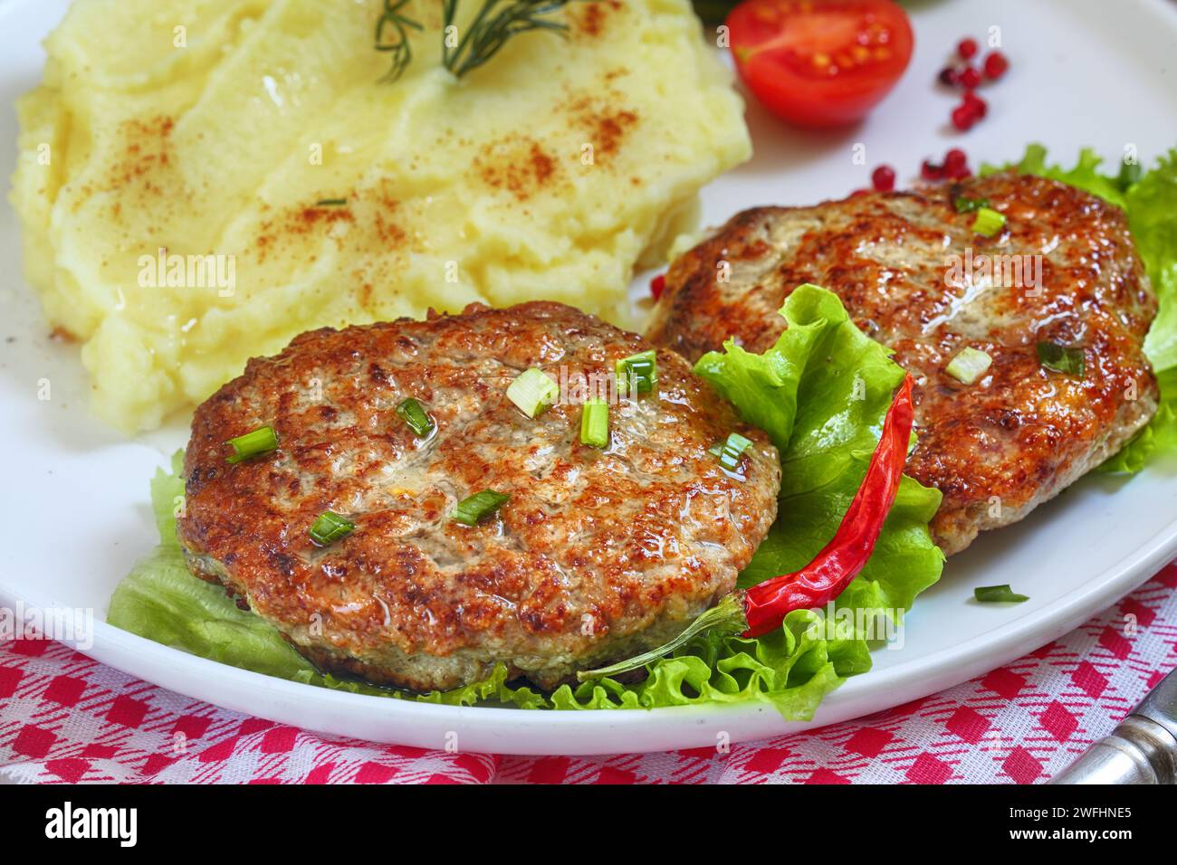 Schnitzel mit Kartoffelpüree auf einem Teller auf einer karierten Tischdecke Stockfoto