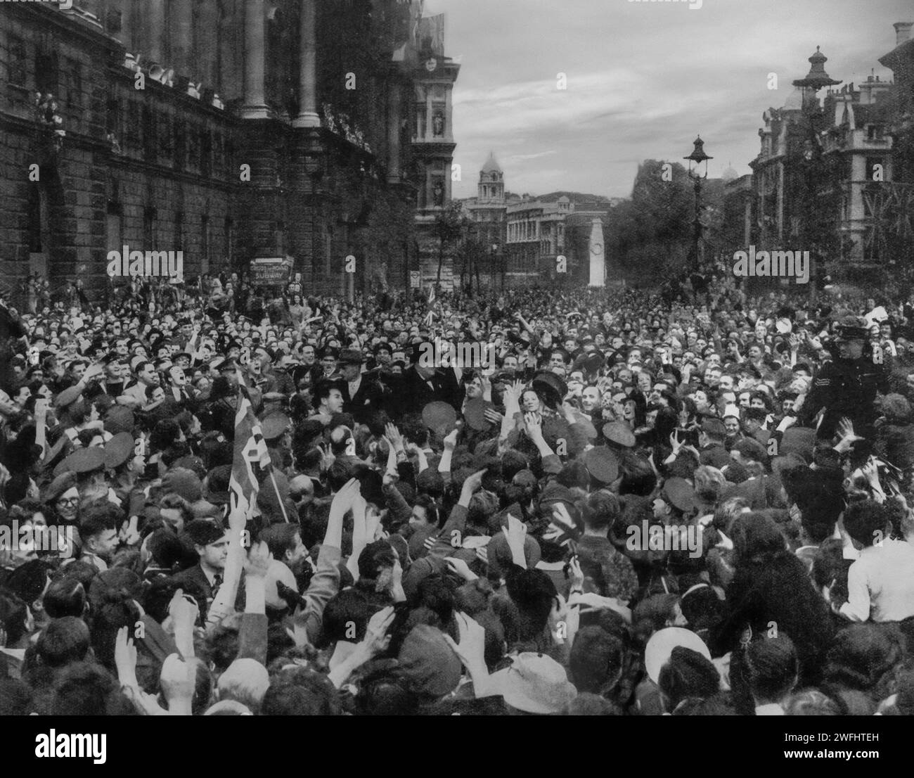 Das Ende des Zweiten Weltkriegs und die Menschenmassen versammeln sich in Whitehall, London, um Premierminister Winston Churchill zum Siegtag in Europa, auch bekannt als VE-Day, am 8. Mai 1945, zu applaudieren und zu jubeln. Stockfoto