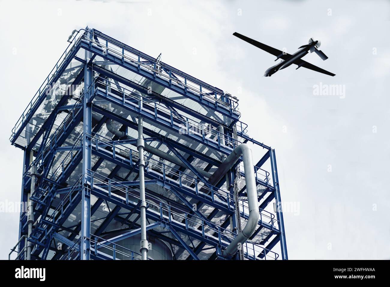 Militärdrohne über dem industriellen Öllagerturm, Drohnenangriff. Stockfoto