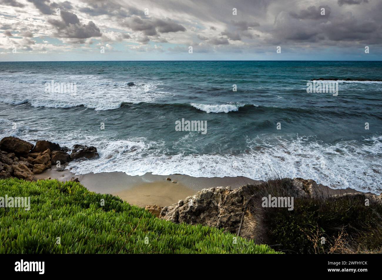 Stürmisches Mittelmeer in Paphos, Zypern. Felsiger Strand, Winter, Sturmwolken am Himmel. Stockfoto