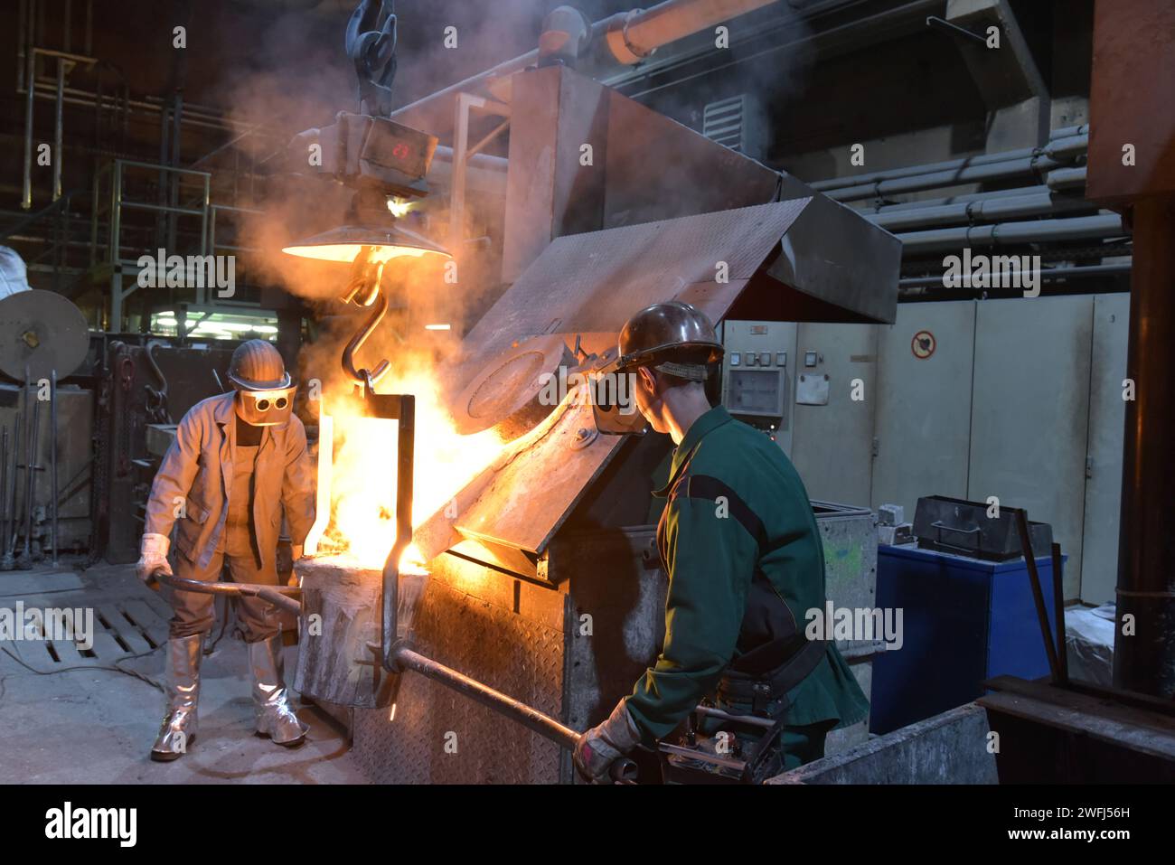 Arbeitnehmer in einer Gießerei gießen ein Werkstück aus Metall - Sicherheit bei der Arbeit und Teamarbeit Stockfoto