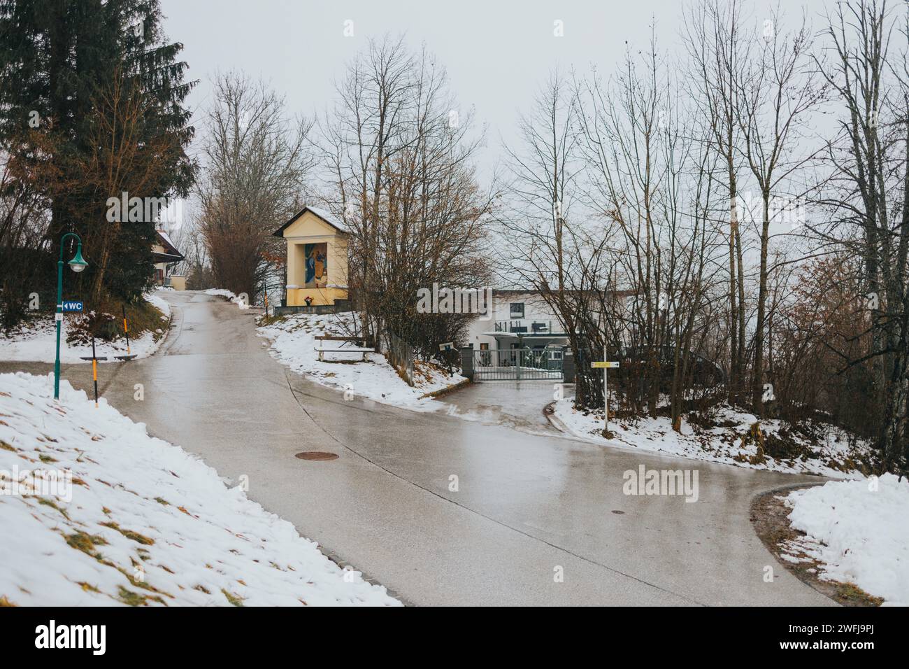 Winterszene mit schneebedeckter Straße und charmantem Haus Stockfoto