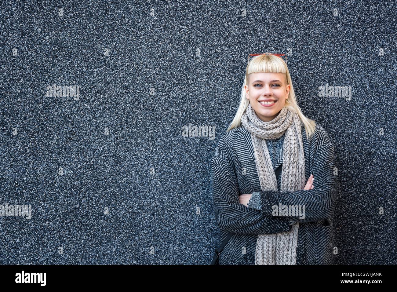 Junge, stilvolle, niedliche Hippie-Frau, die auf der Straße an einer schwarzen Wand steht. Millennial Hipster Girl Porträt draußen, außerhalb des Bürogebäudes. Fashi Stockfoto