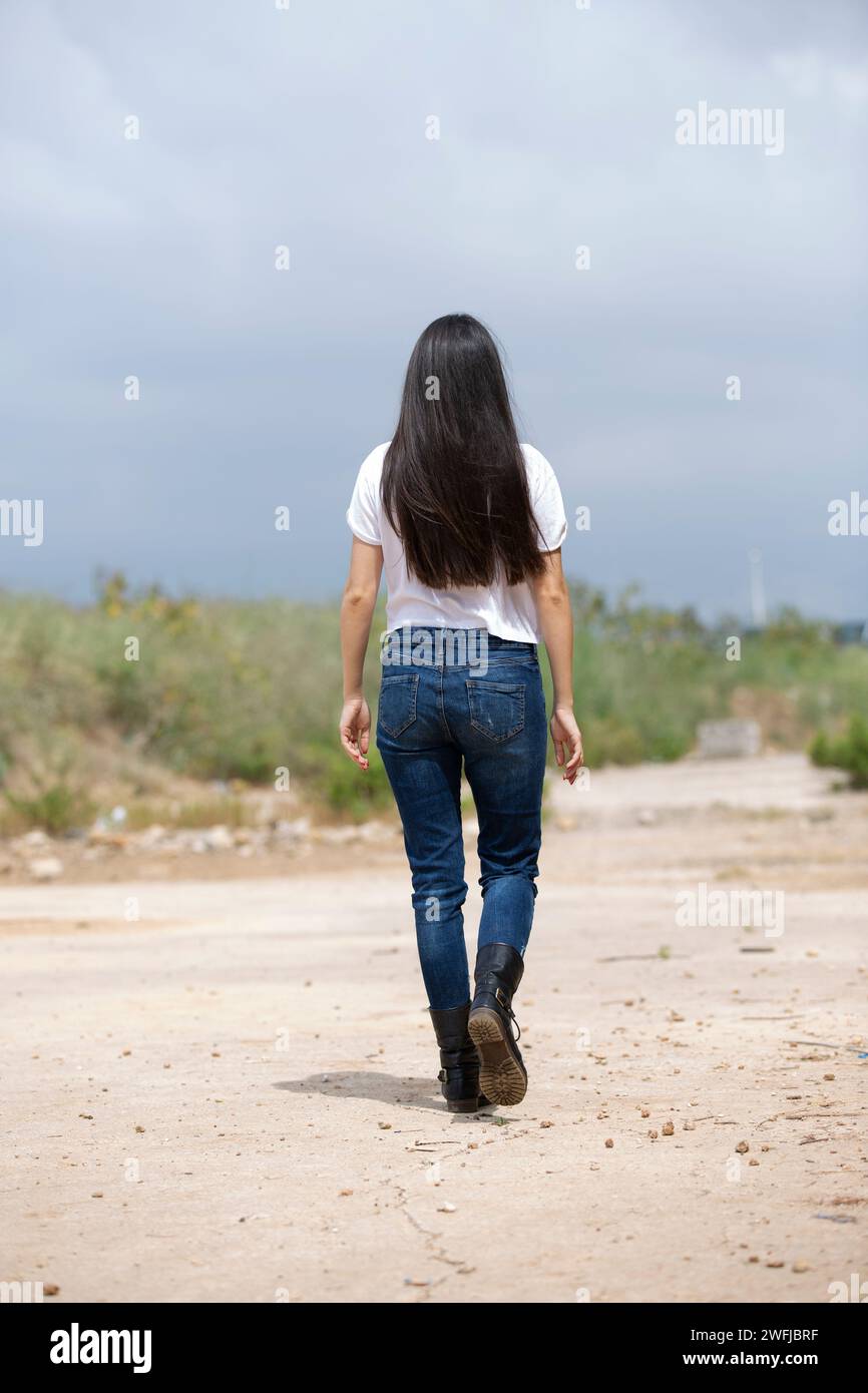 Rückansicht einer schlanken Frau, die draußen weggeht Stockfoto
