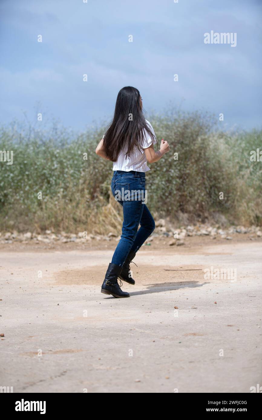 Seitenansicht einer jungen Frau, die draußen wegläuft Stockfoto