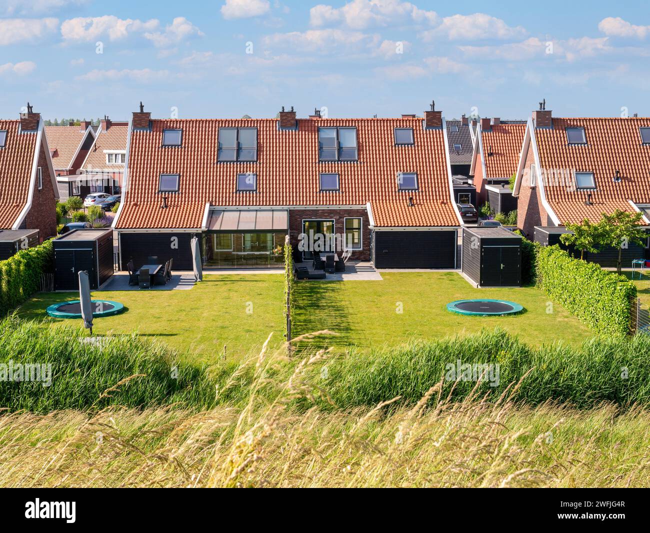Zwei Doppelhaushälften mit Rasen und eingesunkenem rundem Trampolin im Garten im Hinterhof, Colijnsplaat, Noord-Beveland, Zeeland, Niederlande Stockfoto
