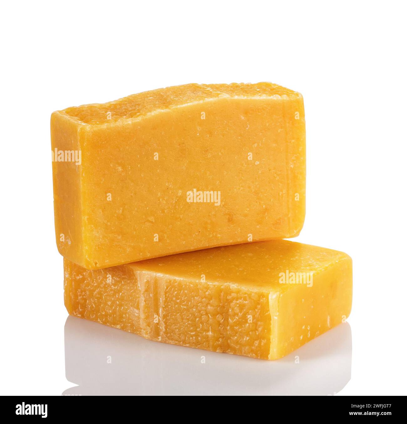 Handgefertigte Bio-Seife aus natürlichen Produkten. Zwei Seifenriegel mit orangefarbenem und bernsteinfarbenem Pulver auf weißem Hintergrund. Stockfoto