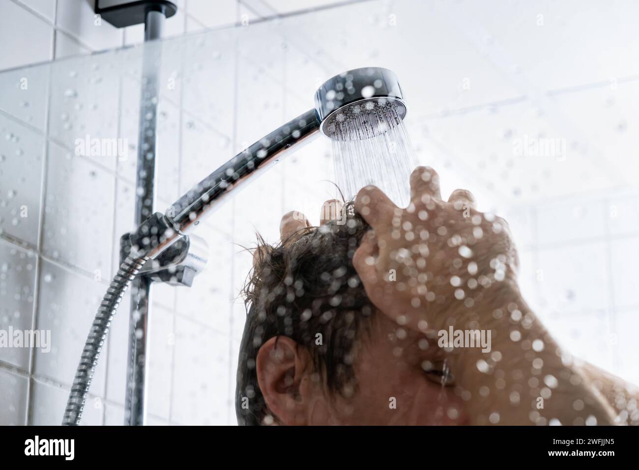 Haarwäsche mit Shampoo. Mann in Dusche. Kaltes oder heißes Wasser. Conditioner, Gel oder Schaum. Konzept für Haarlinien, Verlust, Schuppen oder Schäden. Trockene juckende Kopfhaut. Stockfoto