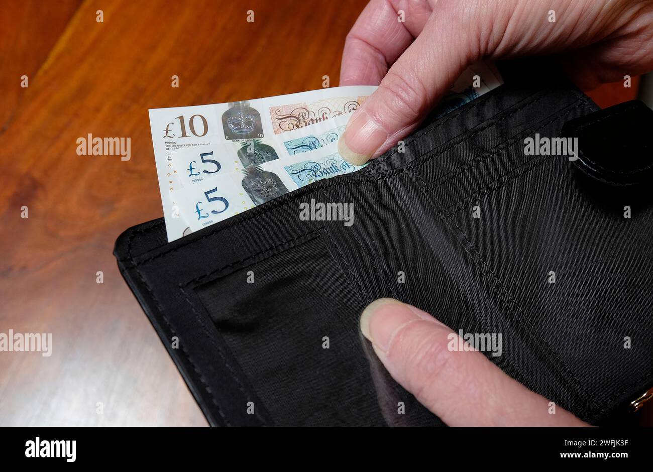 Weibliche Person, die britisches Geld aus der Brieftasche nimmt Stockfoto