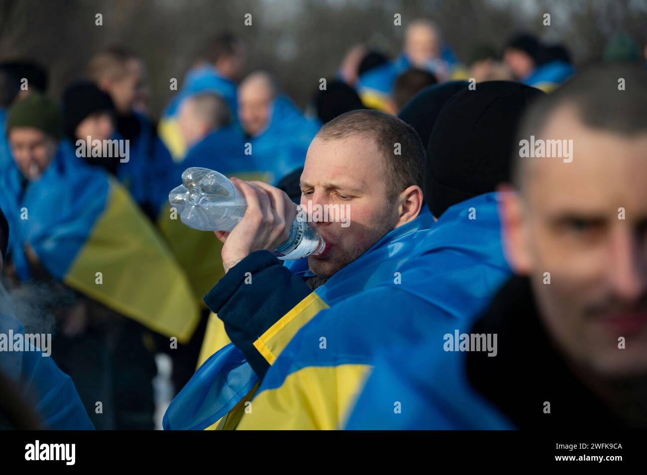 Bakhmut, Ukraine. Januar 31, 2024. Ein ukrainischer Soldat, der in eine Flagge gewickelt ist, trinkt Wasser, nachdem er nach einem Kriegsgefangenenaustausch zwischen Russland und der Ukraine am 31. Januar 2024 an einem unbekannten Ort nach Hause zurückgekommen ist. Der Austausch war die 50. Rückkehr von Kriegsgefangenen, an der 207 ukrainische Verteidiger beteiligt waren. Quelle: Pool Photo/Ukrainische Präsidentenpresse/Alamy Live News Stockfoto