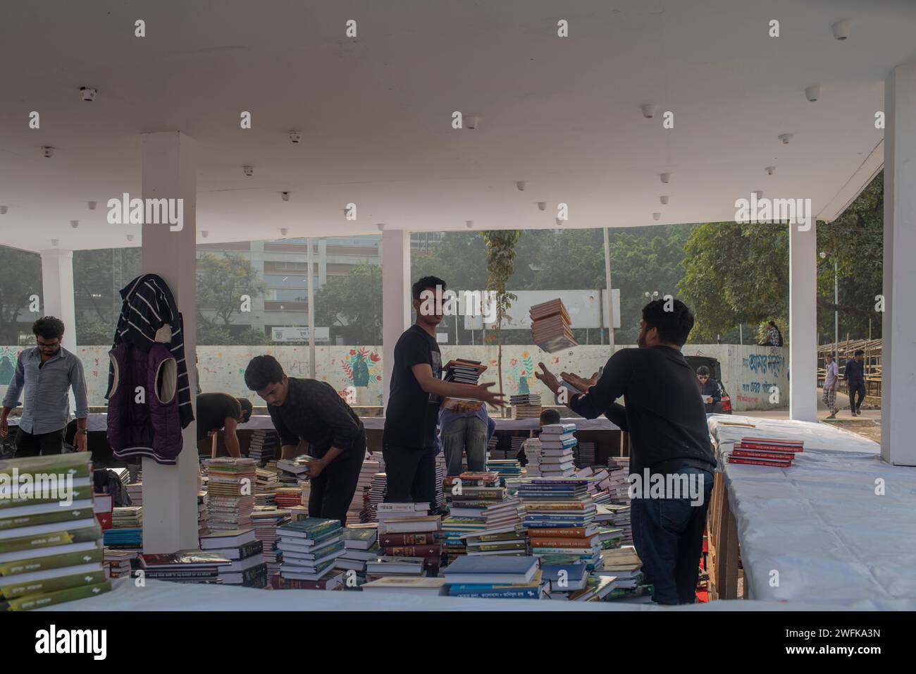 Buchverkäufer sind damit beschäftigt, die Bücher vor der Eröffnung der Amar Ekushey Buchmesse in Dhaka Suhrawardy Udyan zu arrangieren. Stockfoto