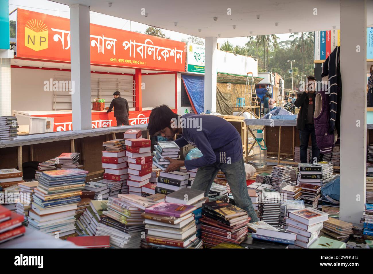 Dhaka, Bangladesch. Januar 31, 2024. Vor der Eröffnung der Amar Ekushey Buchmesse in Dhaka's Suhrawardy Udyan arrangiert ein Junge Bücher an einem Stand. (Credit Image: © Sazzad Hossain/SOPA Images via ZUMA Press Wire) NUR REDAKTIONELLE VERWENDUNG! Nicht für kommerzielle ZWECKE! Stockfoto