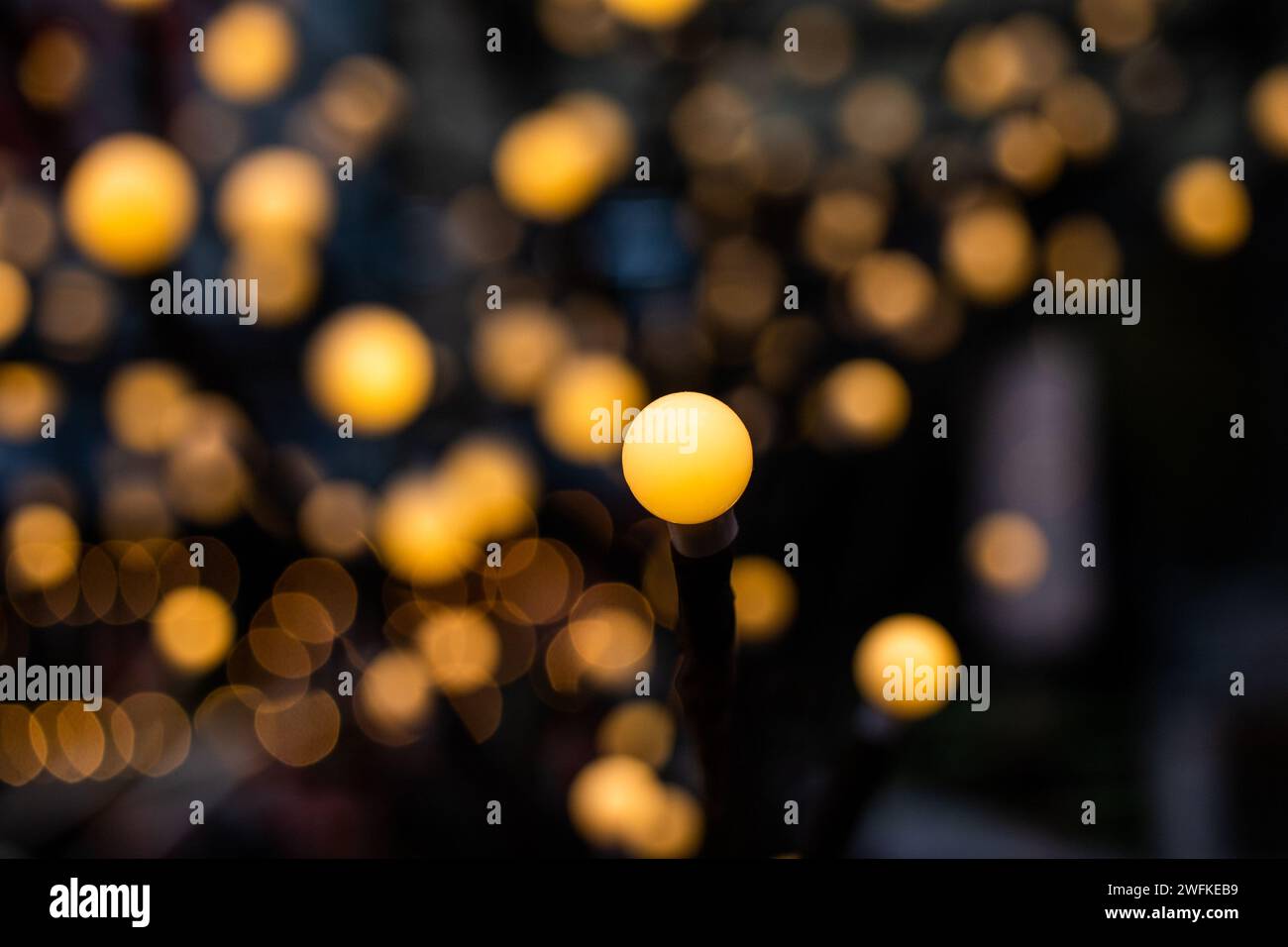Ein gelbes Licht im Fokus und viele verschwommene in einem Bokeh-Hintergrund können als horizontale Ausrichtung des Texturhintergrunds verwendet werden. Stockfoto