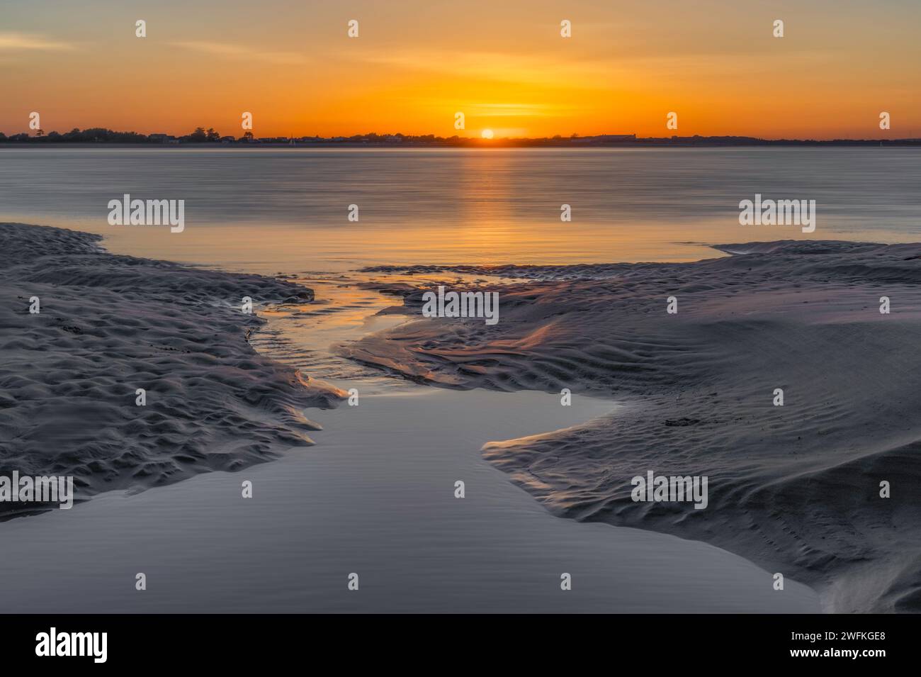 Ein weiterer atemberaubender Sonnenuntergang vom West Wittering Beach, der skulpturalen Sand freilegt und über das Wasser in Richtung Hayling Island blickt Stockfoto