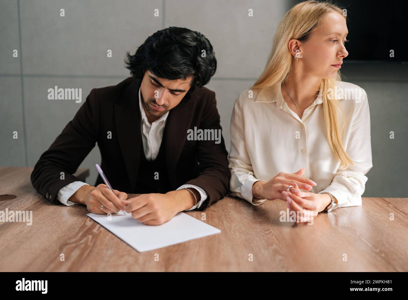 Porträt von traurigen Ehepaaren, die Dekrete unterzeichnen und sich im Büro der Anwälte am Schreibtisch scheiden lassen. Unglückliche Trennung der verheirateten Familie Ende Stockfoto