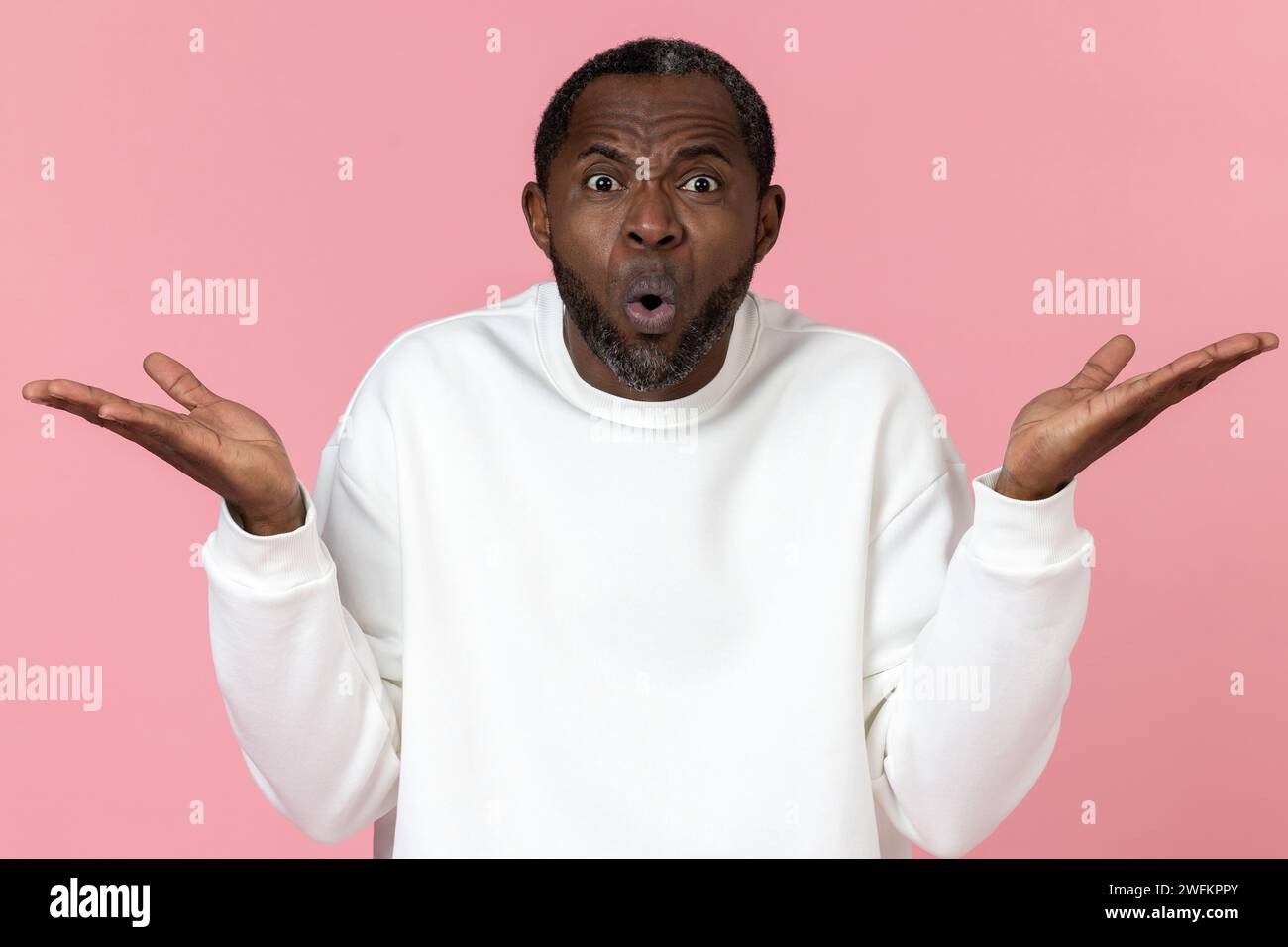 Überraschter schwarzer Mann mit weißem Sweatshirt mit zuckenden Schultern Stockfoto