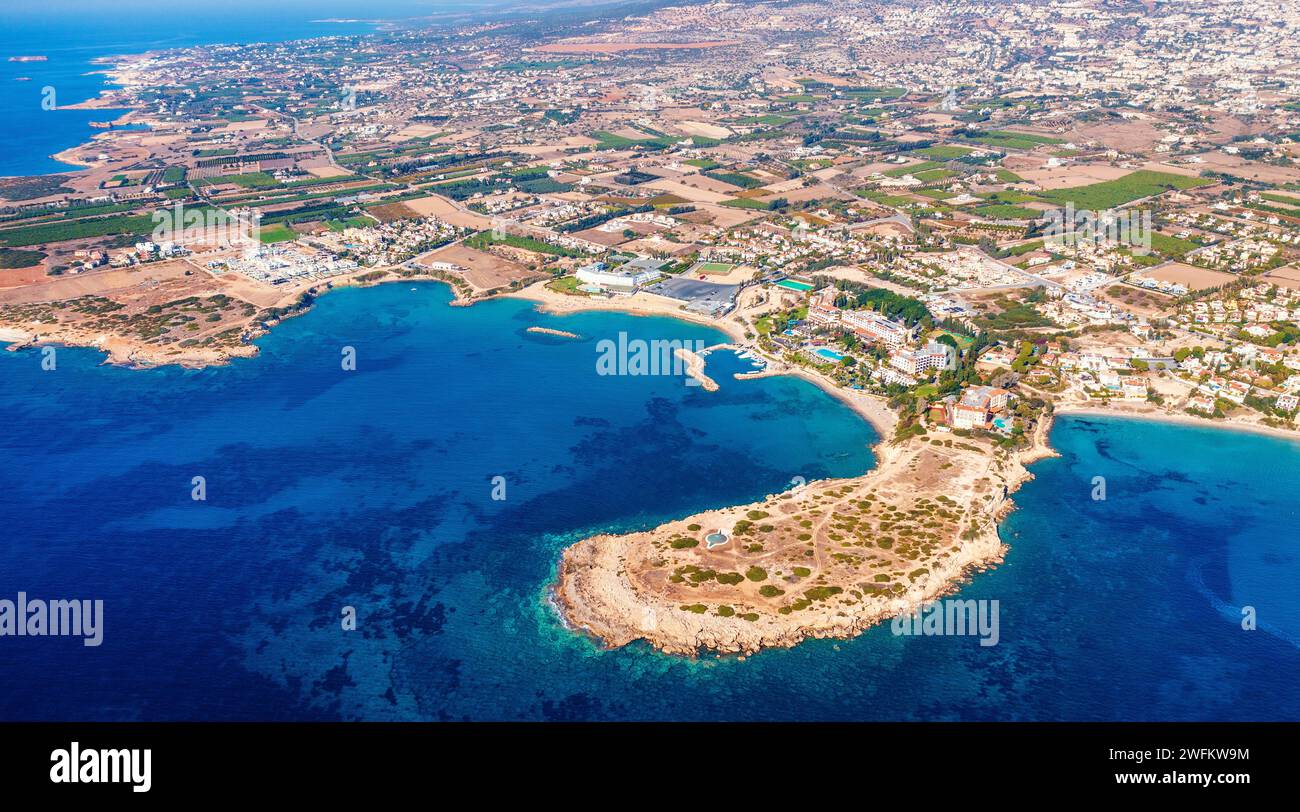 Blick aus der Vogelperspektive auf die zyprische Küstenregion mit tiefblauem Meer und zerklüfteter Küste mit Bucht, Hotel und Stränden unter hellem Sonnenlicht Stockfoto