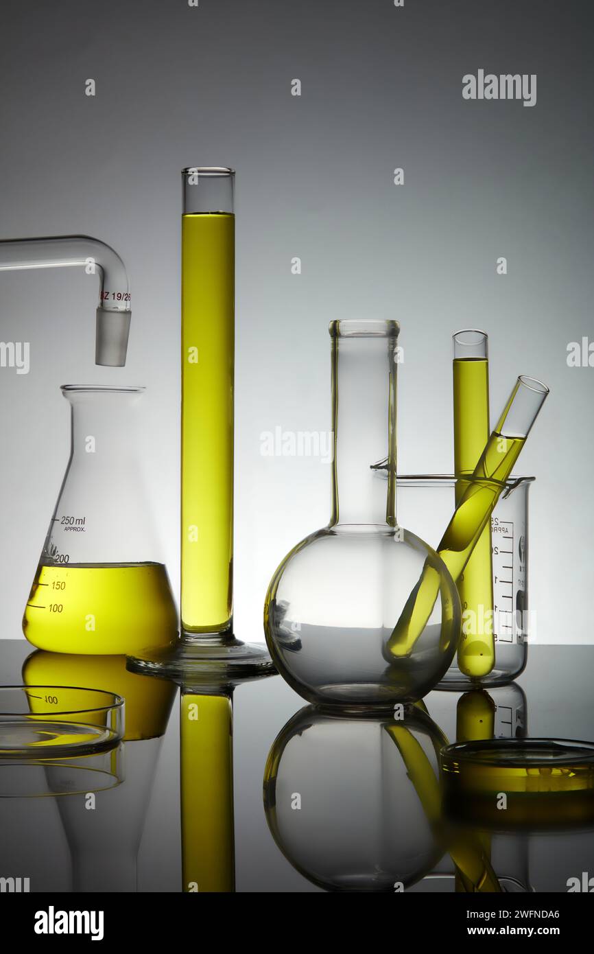 Laborglasgeräte mit gelber Flüssigkeit und Hintergrundbeleuchtung. Wissenschaftslaborforschungskonzept. Stockfoto