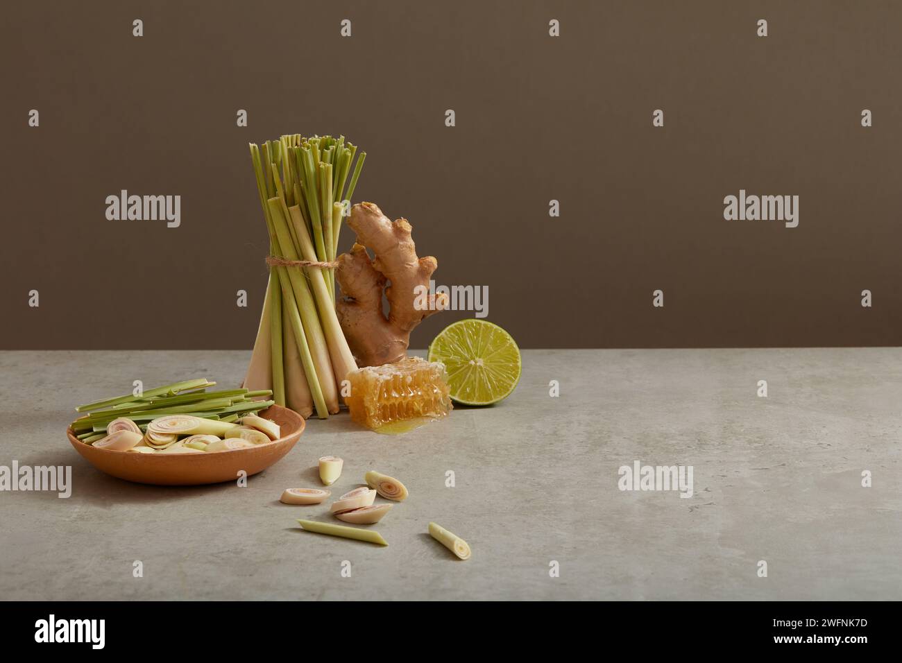 Ein Ingwer, eine Zitronenscheibe und viele Zitronengras werden auf minimalistischem Hintergrund mit Bienenwachs dargestellt. Leerzeichen, um Text hinzuzufügen oder das Produkt zu befördern. Kräuter Stockfoto