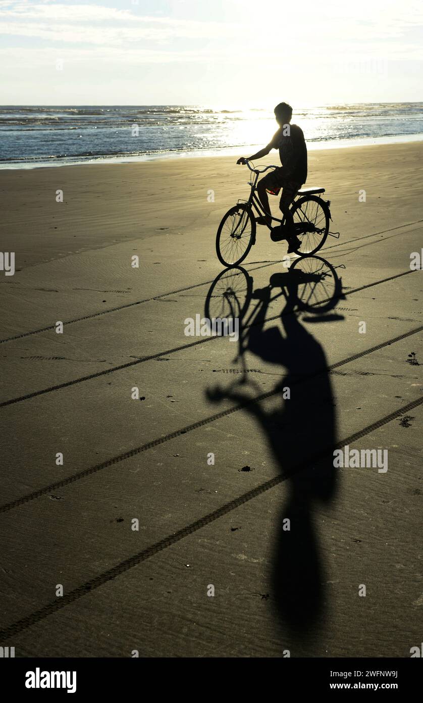 Radfahren am Strand bei Sonnenuntergang in Sittwer, Rakhine State, Myanmar. Stockfoto