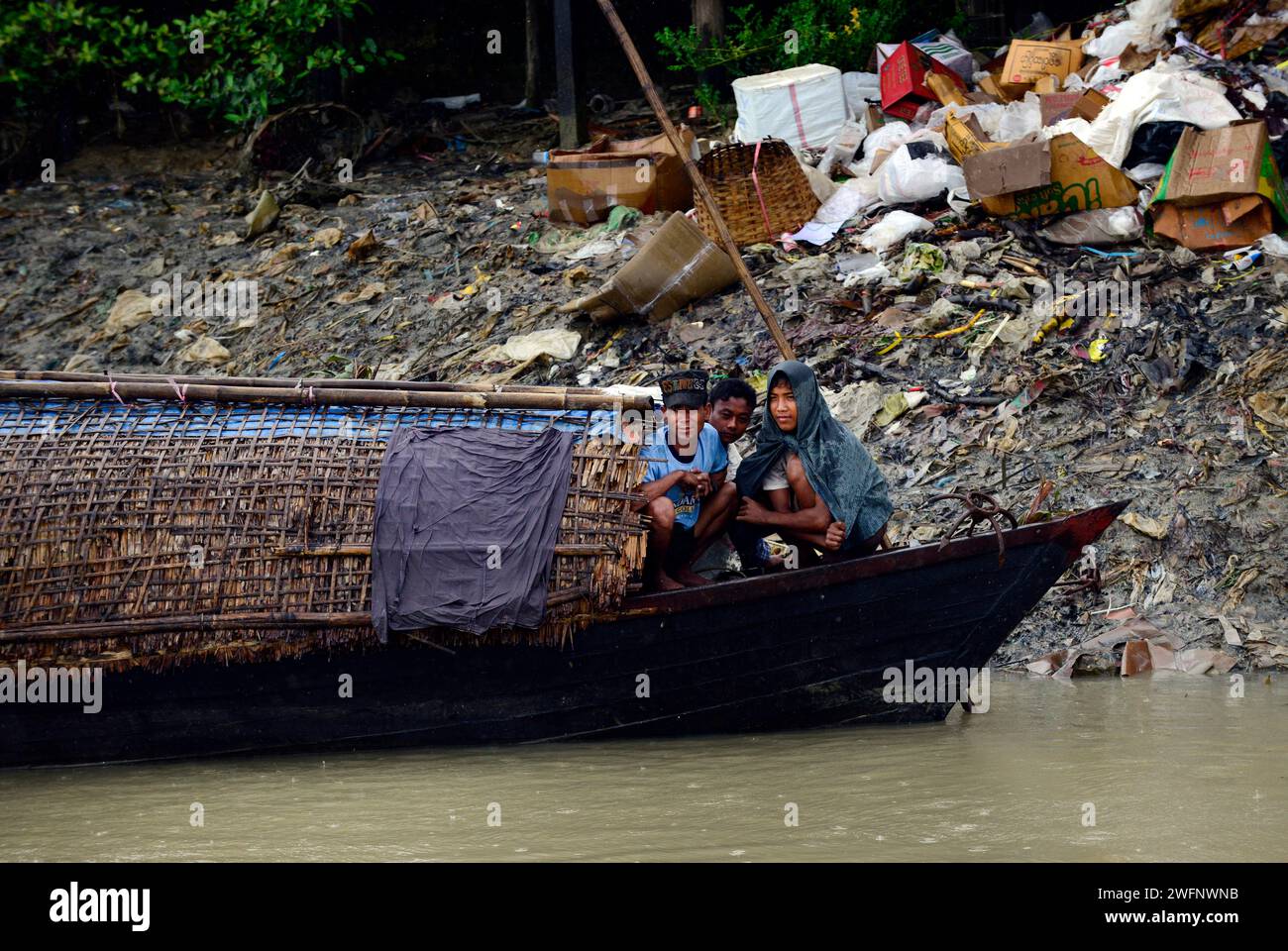 Arakanesen, die während der Monsunsaison Schutz vor dem starken Regen suchen. Kaladan River, Rakhine State, Myanmar. Stockfoto
