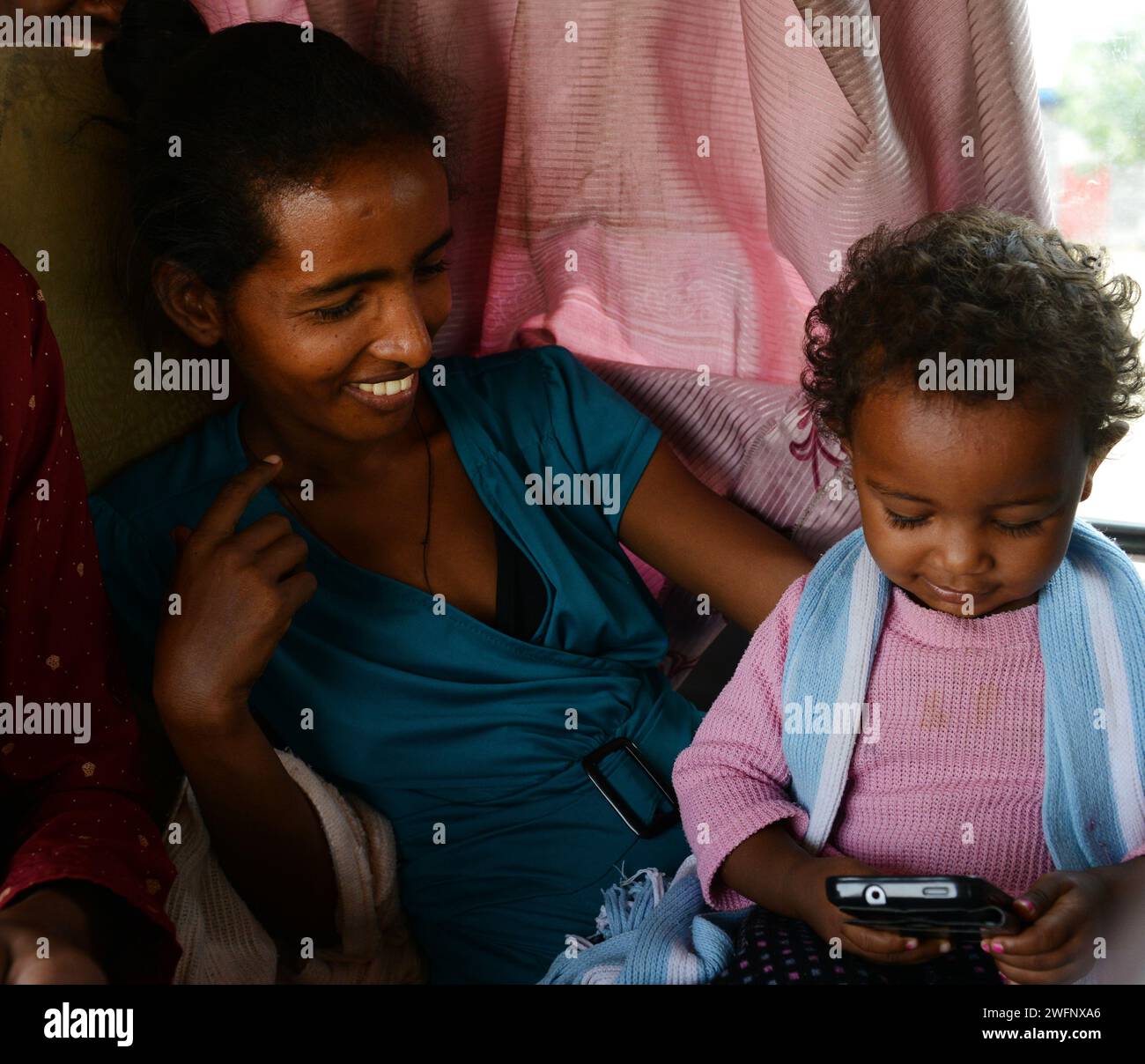 Ein äthiopisches Kleinkind, das das Smartphone ihrer Mutter benutzt. Stockfoto