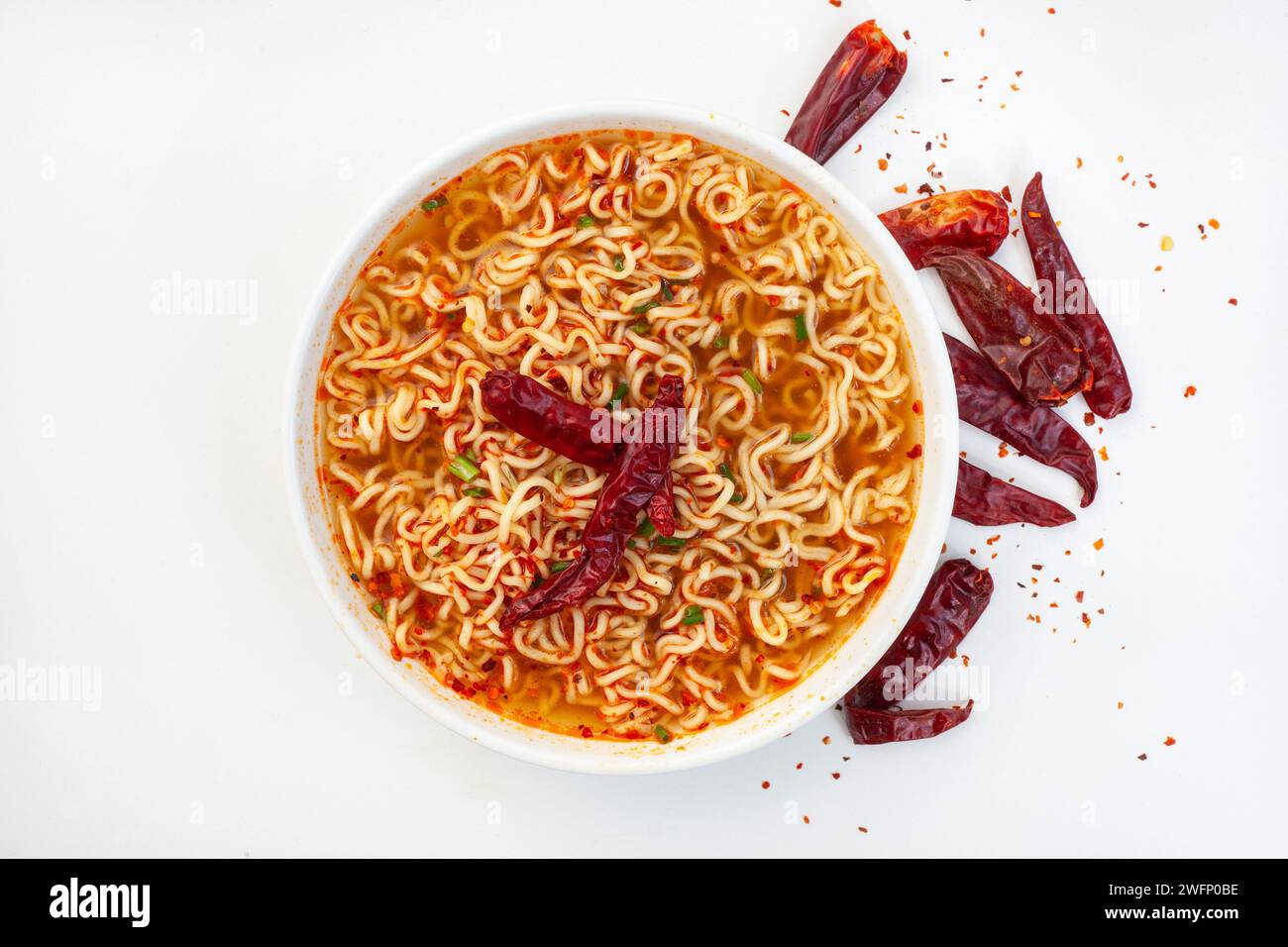 Scharfe Instant Nudeln oder Ramen mit getrocknetem Chili auf weißem Hintergrund mit Kopierraum. Flache Lage, Draufsicht. Stockfoto