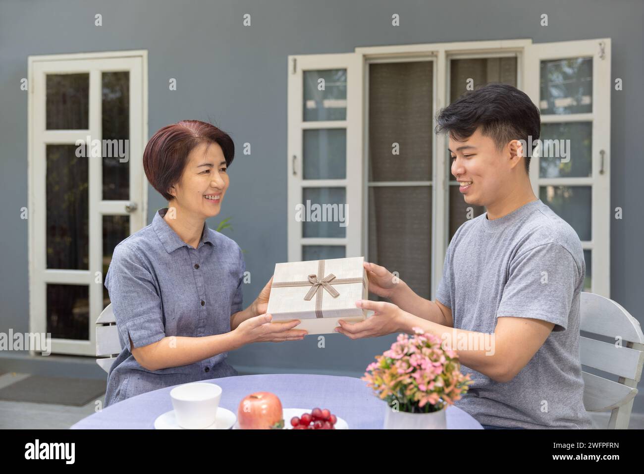 Der erwachsene Sohn schenkt Mutter am Muttertag ein Geschenk. Stockfoto