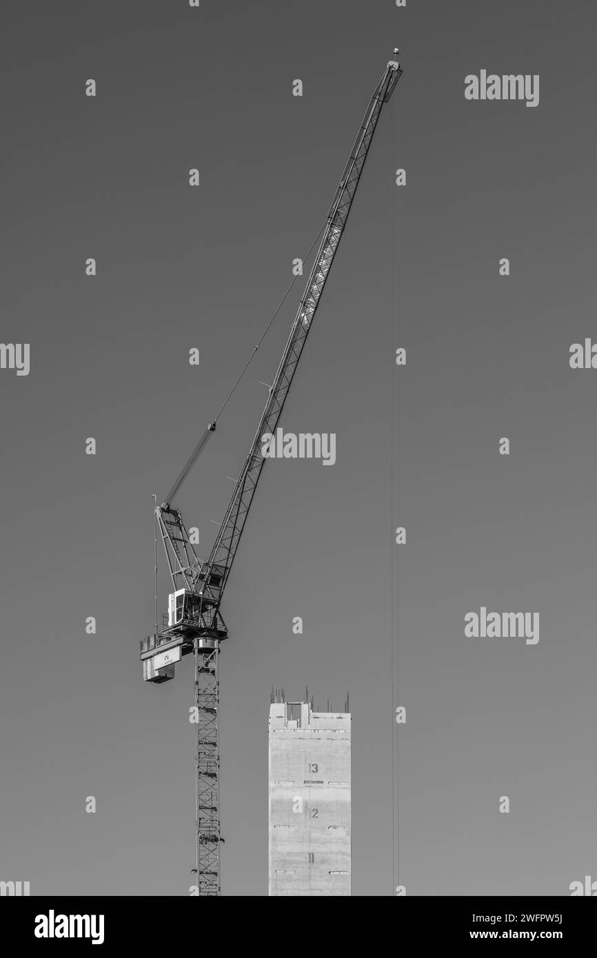 Schwarzweiß-Portraitbild eines Turmdrehkrans über dem Betonkernturm einer Victoria Construction-Entwicklung in Manchester, Großbritannien. Stockfoto