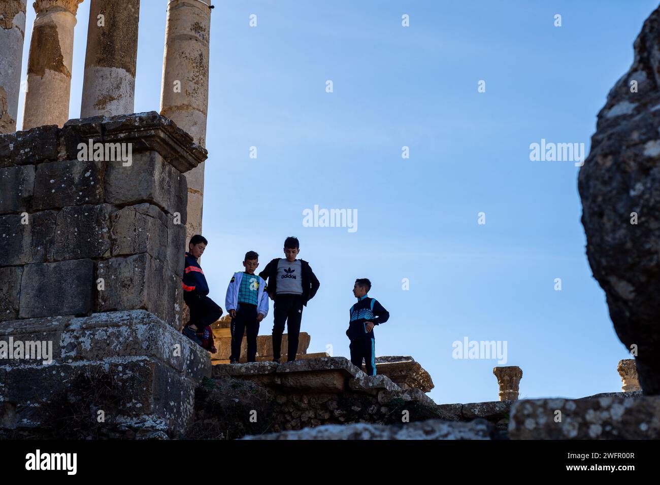 Flacher Blick auf kleine Kinder auf römischen Ruinen vor dem Himmel in der antiken römischen Stadt Djemila. Stockfoto