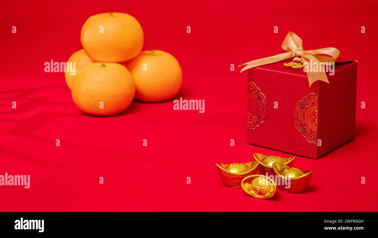 Chinesischer roter Hintergrund für das Mondneujahr. Antike chinesische Barren aus Barren, orange, rote Geschenkbox mit goldener Schleife zum chinesischen Neujahrsfest Stockfoto