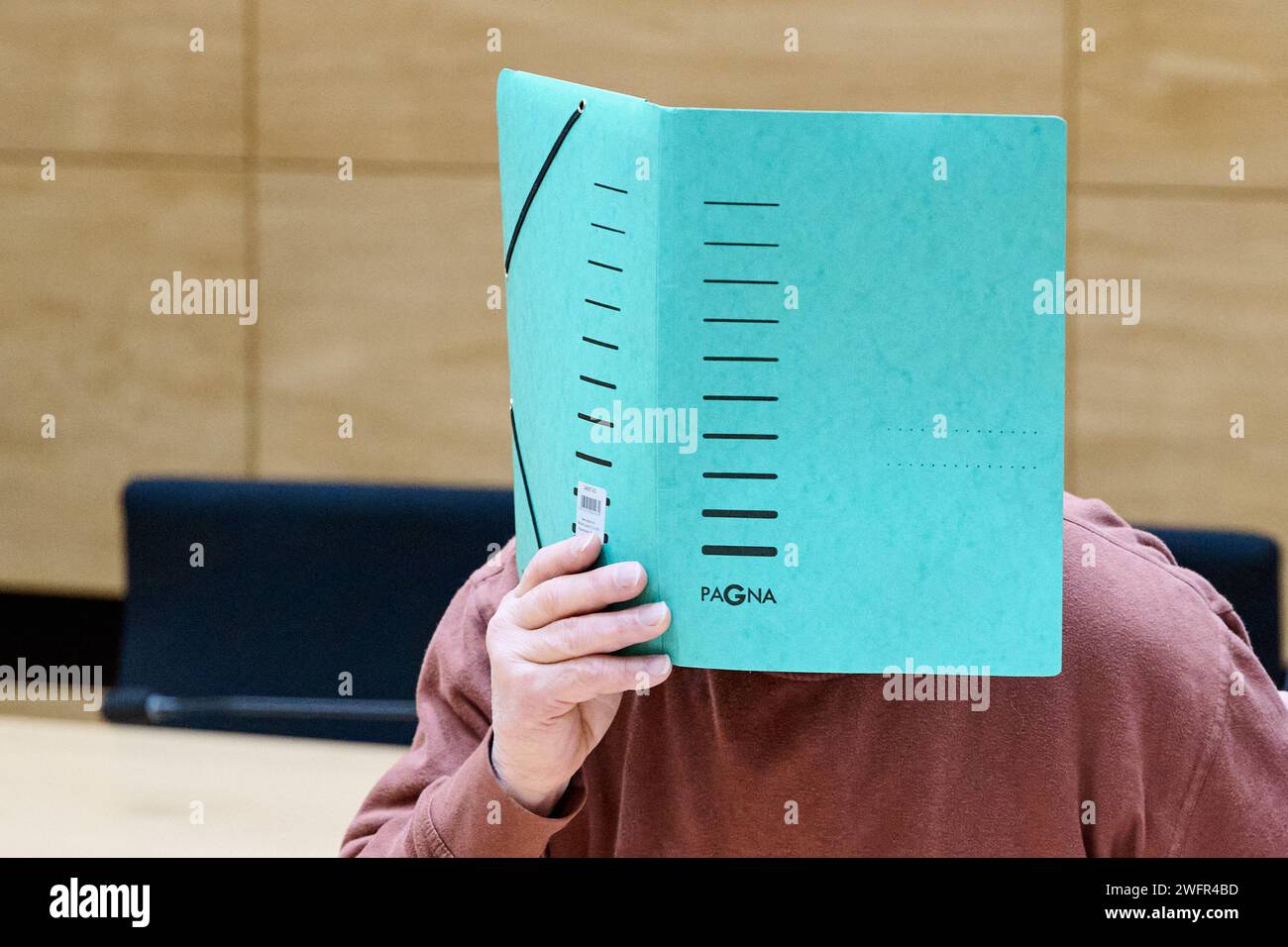 Bielefeld, Deutschland. Februar 2024. Der Angeklagte sitzt vor dem Bezirksgericht und versteckt sein Gesicht hinter einer Akte. Die Staatsanwaltschaft wirft dem 73-Jährigen aus Halle/Westfalen vor, seine getrennte Frau im Juli 2023 ermordet zu haben. Der Mann soll die Frau erwürgt haben und sie dann in einem Grabgraben in einem Waldgebiet bei Halle/Westfalen versteckt haben. Quelle: Bernd Thissen/dpa/Alamy Live News Stockfoto