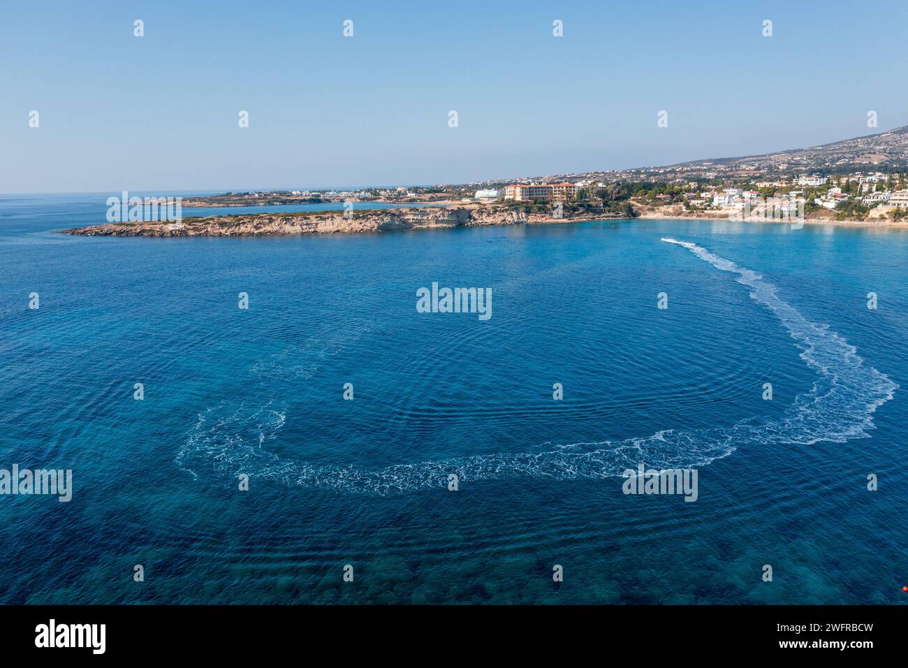 Boot schwimmt im zyprischen Meer in der Nähe des Sandstrandes. Sommerreisen und mediterrane Resorts. Stockfoto